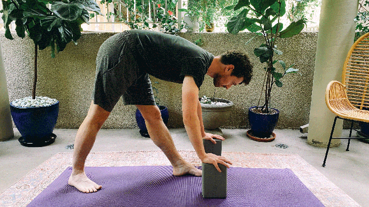 Man practicing yoga on a mat with hands on blocks