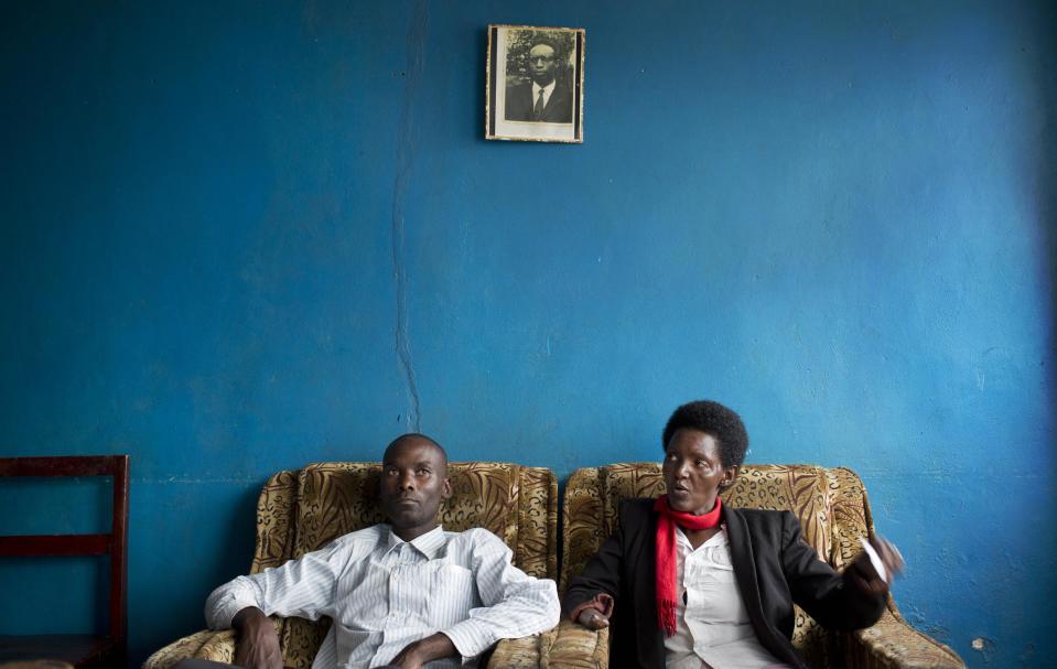 In this photo taken Wednesday, March 26, 2014, Emmanuel Ndayisaba, left, and Alice Mukarurinda, recount their experiences of the Rwandan genocide as they sit under a photograph of Alice's father, who was elsewhere at the time and also managed to survive, at Alice's house in Nyamata, Rwanda. She lost her baby daughter and her right hand to a manic killing spree. He wielded the machete that took both. Yet today, despite coming from opposite sides of an unspeakable shared past, Alice Mukarurinda and Emmanuel Ndayisaba are friends. She is the treasurer and he the vice president of a group that builds simple brick houses for genocide survivors. They live near each other and shop at the same market. Their story of ethnic violence, extreme guilt and, to some degree, reconciliation is the story of Rwanda today, 20 years after its Hutu majority killed more than 1 million Tutsis and moderate Hutus. The Rwandan government is still accused by human rights groups of holding an iron grip on power, stifling dissent and killing political opponents. But even critics give President Paul Kagame credit for leading the country toward a peace that seemed all but impossible two decades ago. (AP Photo/Ben Curtis)