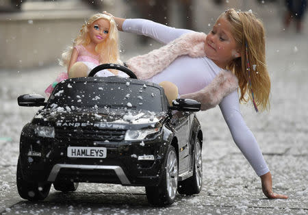 Six year old Lillie reacts as she poses with a children's Range Rover Evoque ride-on car and a Barbie fashion doll, which form part of the selection of predicted top sellers this Christmas at the Hamleys toy store in London, Britain, October 12, 2017. REUTERS/Toby Melville