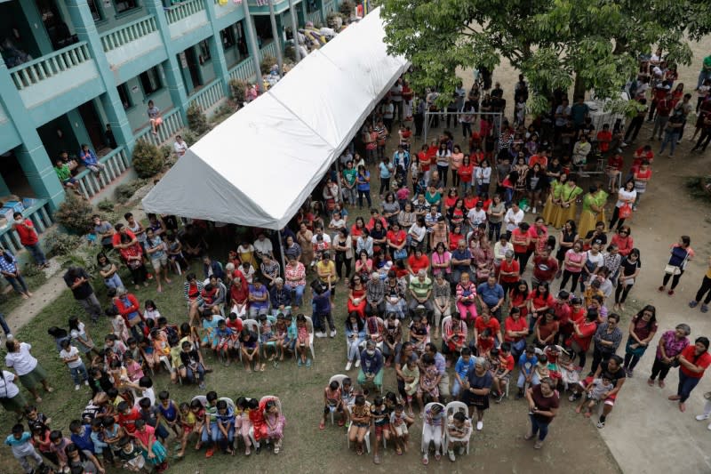 Residents displaced by the erupting Taal Volcano attend a Catholic mass in an evacuation center