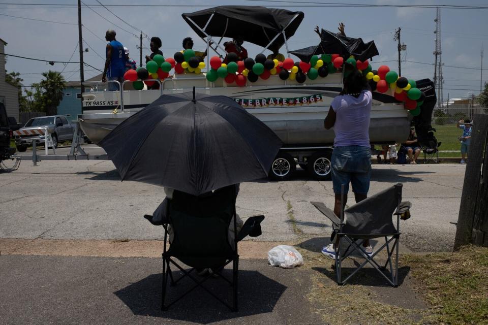 A local resident takes cover from hot weather under an umbrella during the Juneteenth Parade in Galveston, Texas, U.S., June 17, 2023. REUTERS/Adrees Latif