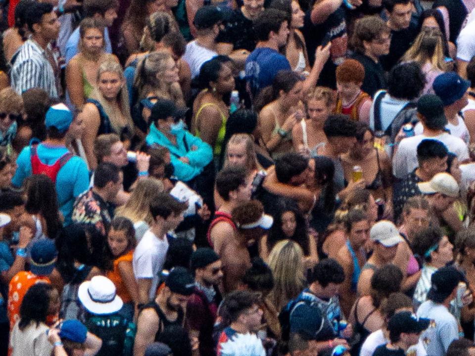 A person wearing a mask and a couple kissing at Lollapalooza 2021