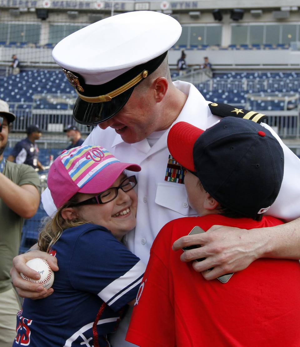 <p>Maddie Cooper, left, 10, and her brother Joey Cooper, 12, from Alexandria, Va., hug their father U.S. Navy Lt. Lewis Cooper as they are surprised by his return from a six-month deployment to Afghanistan, on the field before an interleague baseball game between the Washington Nationals and the Houston Astros at Nationals Park Tuesday, June 17, 2014, in Washington. (AP Photo/Alex Brandon) </p>