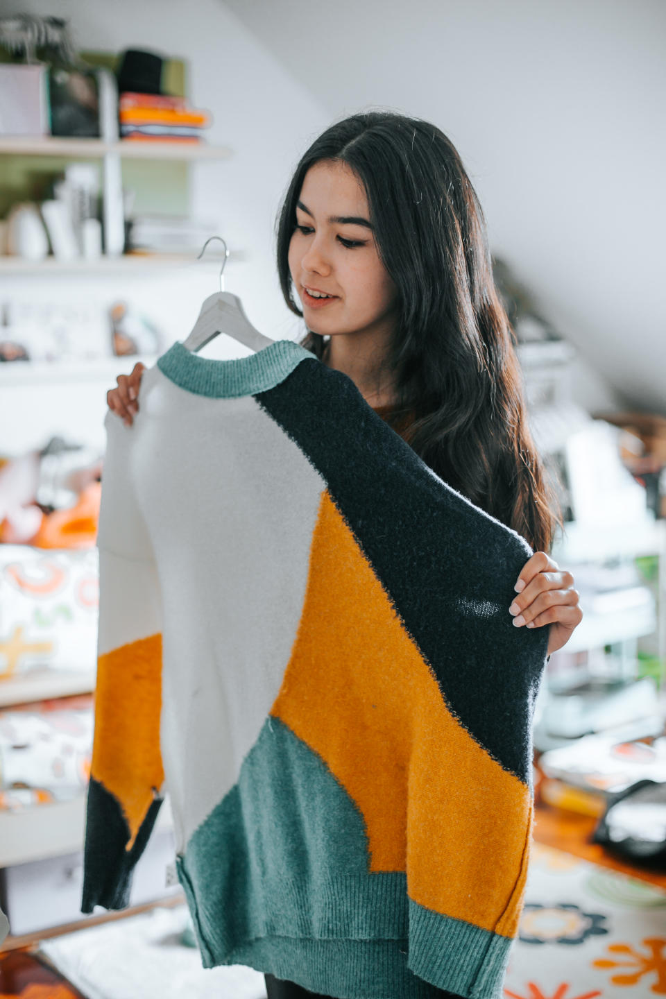 young latina woman choosing a sweater from her closet