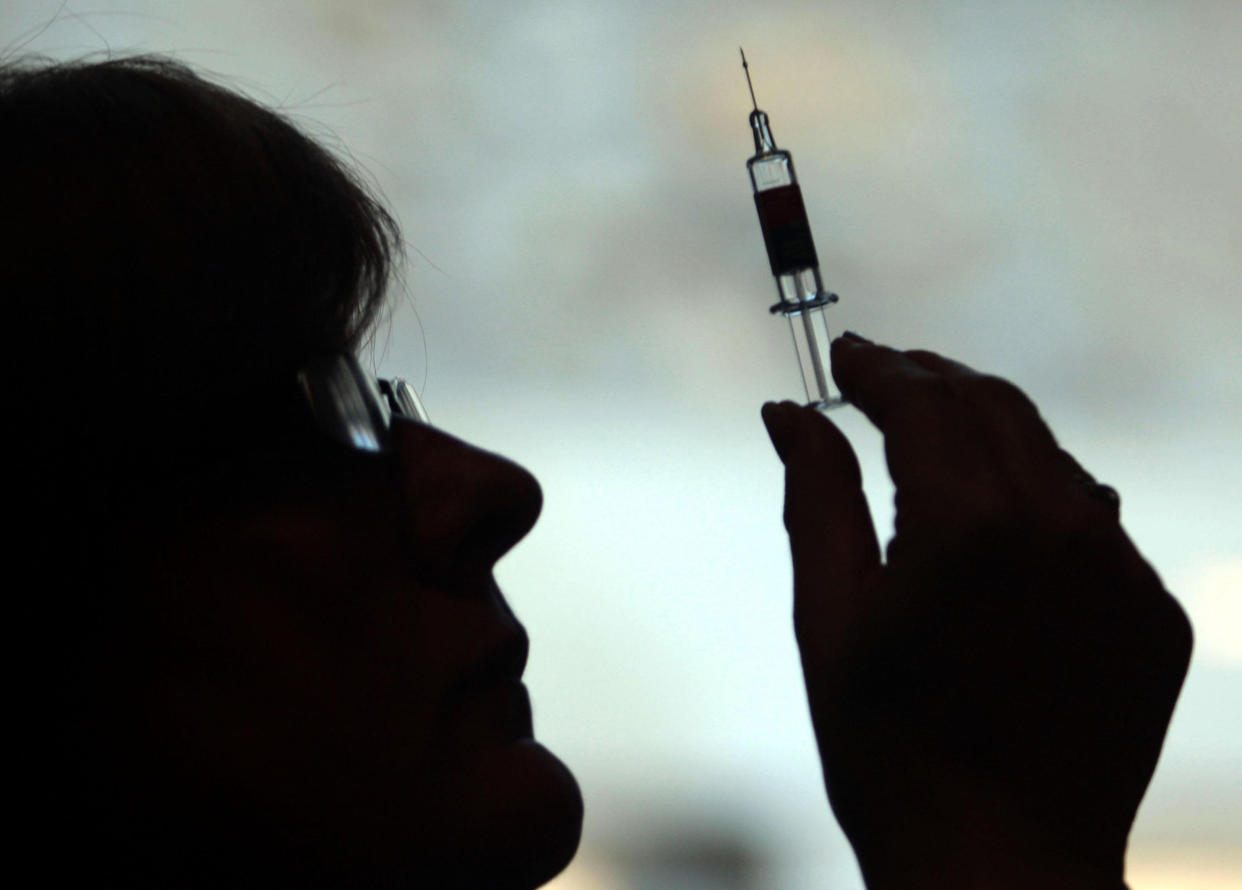 A nurse prepares to give a patient a flu vaccine (PA Images)