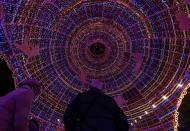 People sit inside a giant Christmas ball as part of Christmas holiday season decorations in Nice December 5, 2013. REUTERS/Eric Gaillard (FRANCE - Tags: SOCIETY TRAVEL)