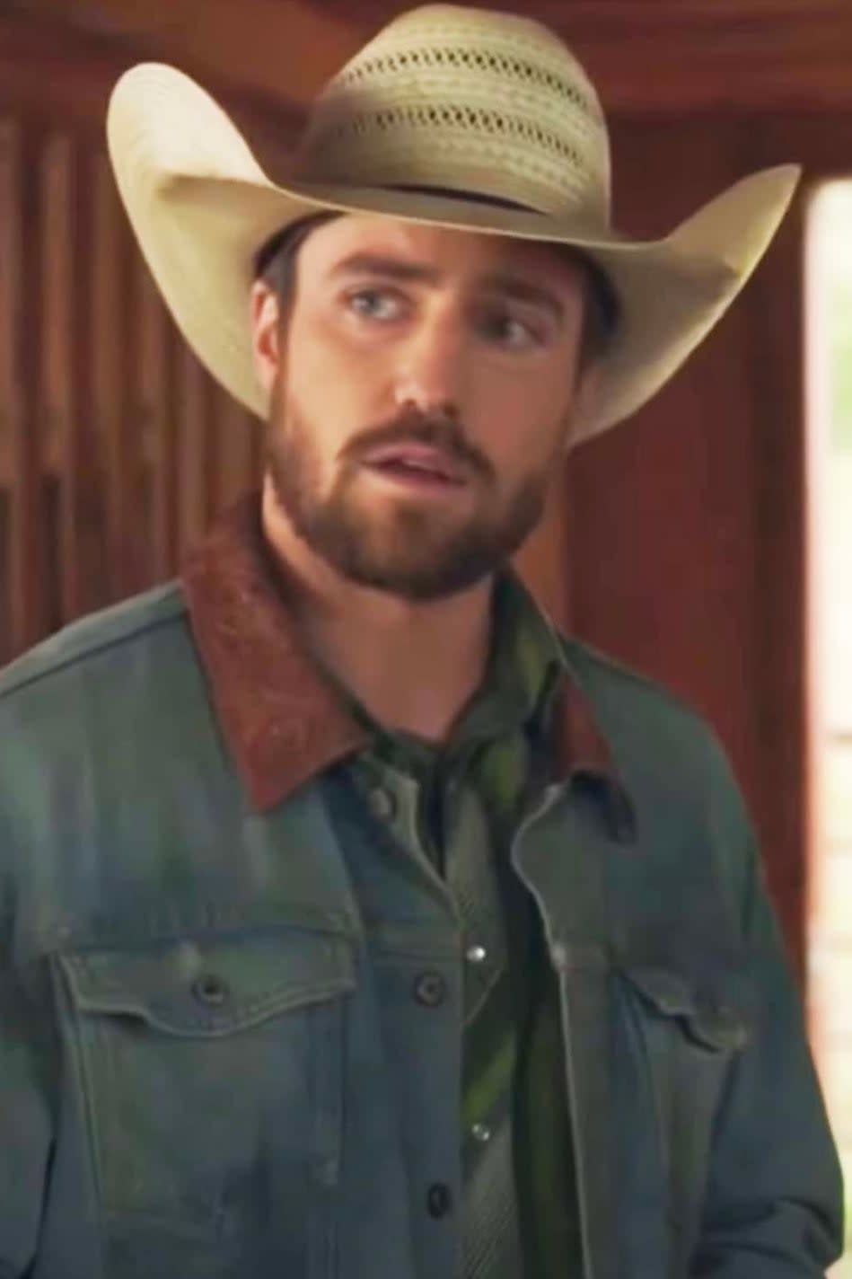 Spencer Lord in Heartland in cowboy attire with hat and denim jacket, in a rustic setting