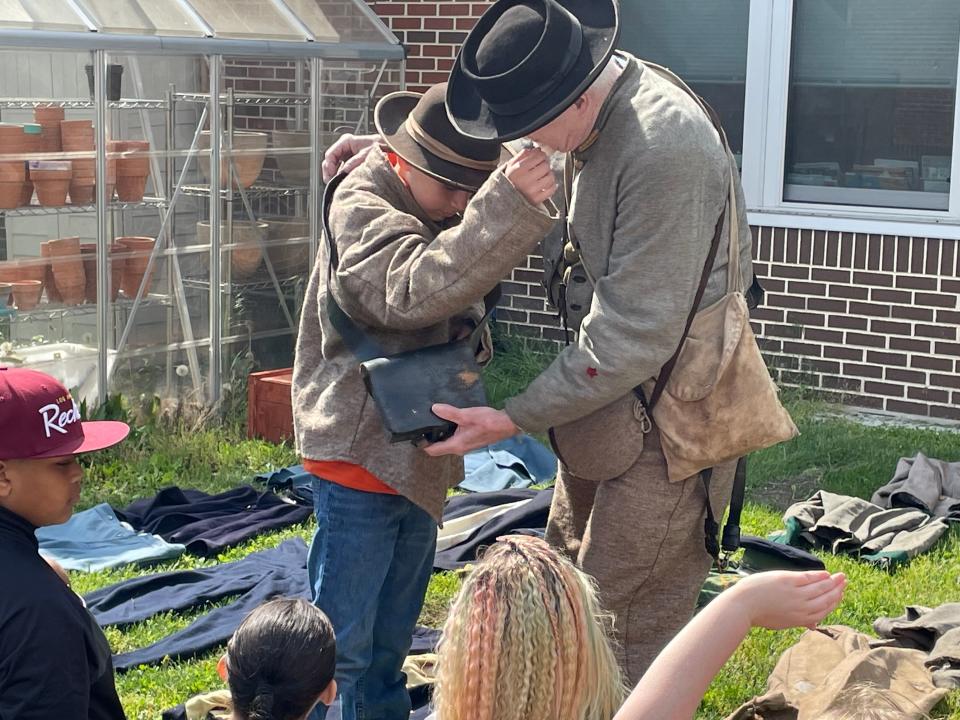 A student tries on a Confederate solider full outfit provided by reenactors visiting Bester Elementary on Wednesday in Hagerstown.