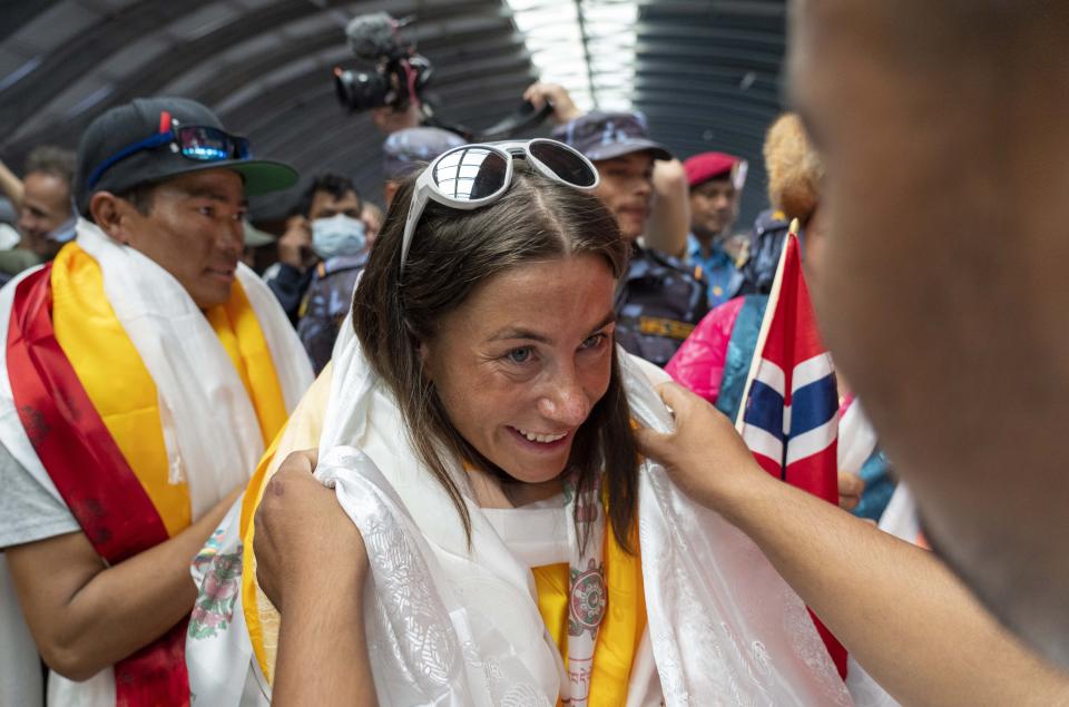 Norwegian woman mountain climber Kristin Harila, center who on Thursday set a new record by scaling the world's 14 highest peaks in 92 days is presented with a shawl as she and her Nepali Sherpa guide Tenjen Sherpa, arrive at the airport in Kathmandu, Nepal, Saturday, Aug.5, 2023. (AP Photo/Niranjan Shreshta)