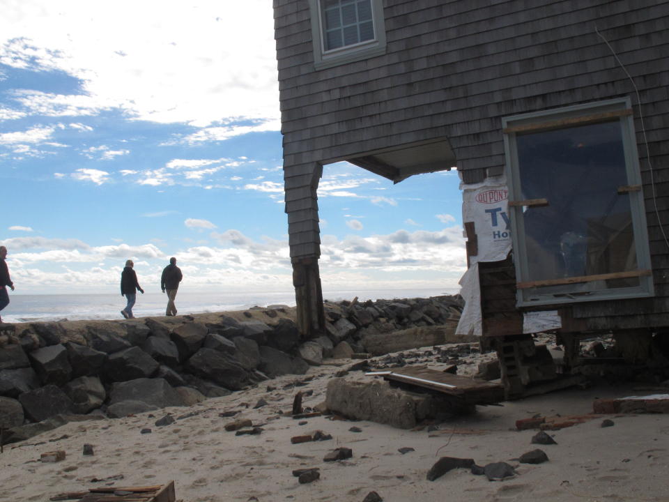 In this Oct. 31, 2012 photo, people walk along a rock wall in Bay Head N.J. two days after Superstorm Sandy hit. On the 10th anniversary of the storm, government officials and residents say much has been done to protect against the next storm, but caution that much more still needs to be done to protect against future storms. (AP Photo/Wayne Parry)