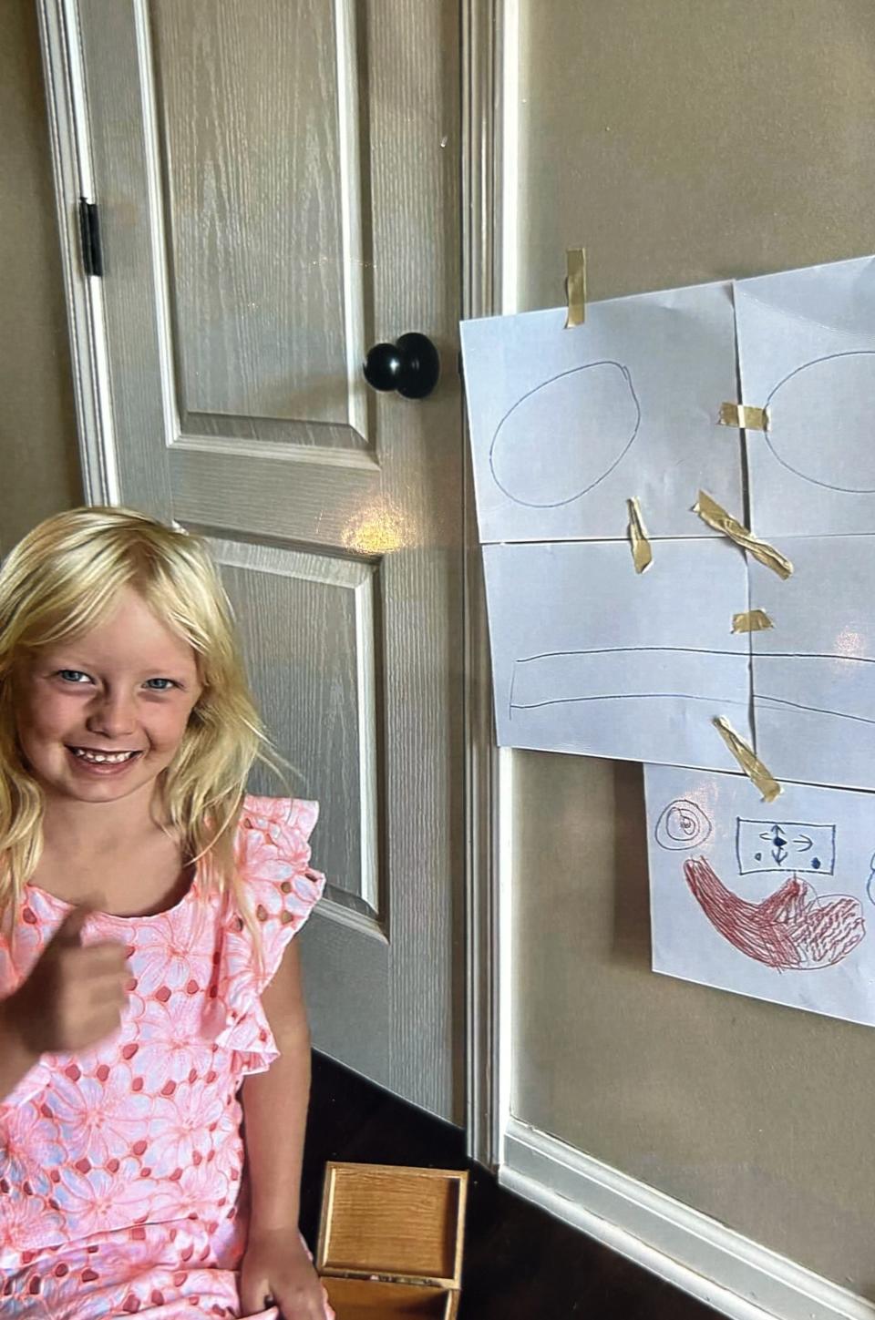 Annie Gotwald stands next to a kindergarten project at home.