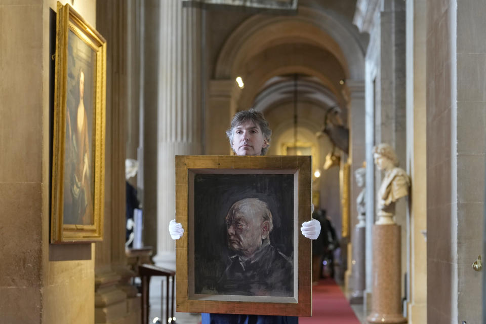 A member of staff from Sotheby's poses for the media with a portrait of the iconic former British Prime Minister Winston Churchill, painted by Graham Sutherland in 1954, at Blenheim Palace, Woodstock, England, Tuesday, April 16, 2024. The portrait will be sold at auction on June 6 with an estimated price of 500-800,000 pounds sterling (US621, 000-1,000,000). Churchill was born at Blenheim Palace on Nov. 30, 1874. (AP Photo/Alastair Grant)