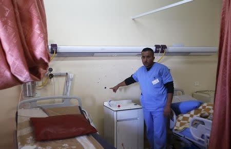 A medic shows to journalists a bullet hole in a wall surrounded by blood stains of a Palestinian man who was killed by Israeli undercover forces during a raid at Al-Ahly hospital in the West Bank city of Hebron November 12, 2015. REUTERS/Mussa Qawasma