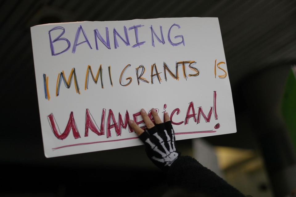 A protester holds up a sign that reads, 'Banning Immigrants is UnAmerican!,' as she stands with others at the Miami International Airport: Getty