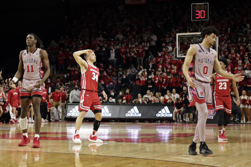 Wisconsin guard Brad Davison (34) reacts after making a 3-point basket between Rutgers guard Geo Baker (0) and center Clifford Omoruyi (11) during the first half of an NCAA college basketball game Saturday, Feb. 26, 2022, in Piscataway, N.J. (AP Photo/Adam Hunger)