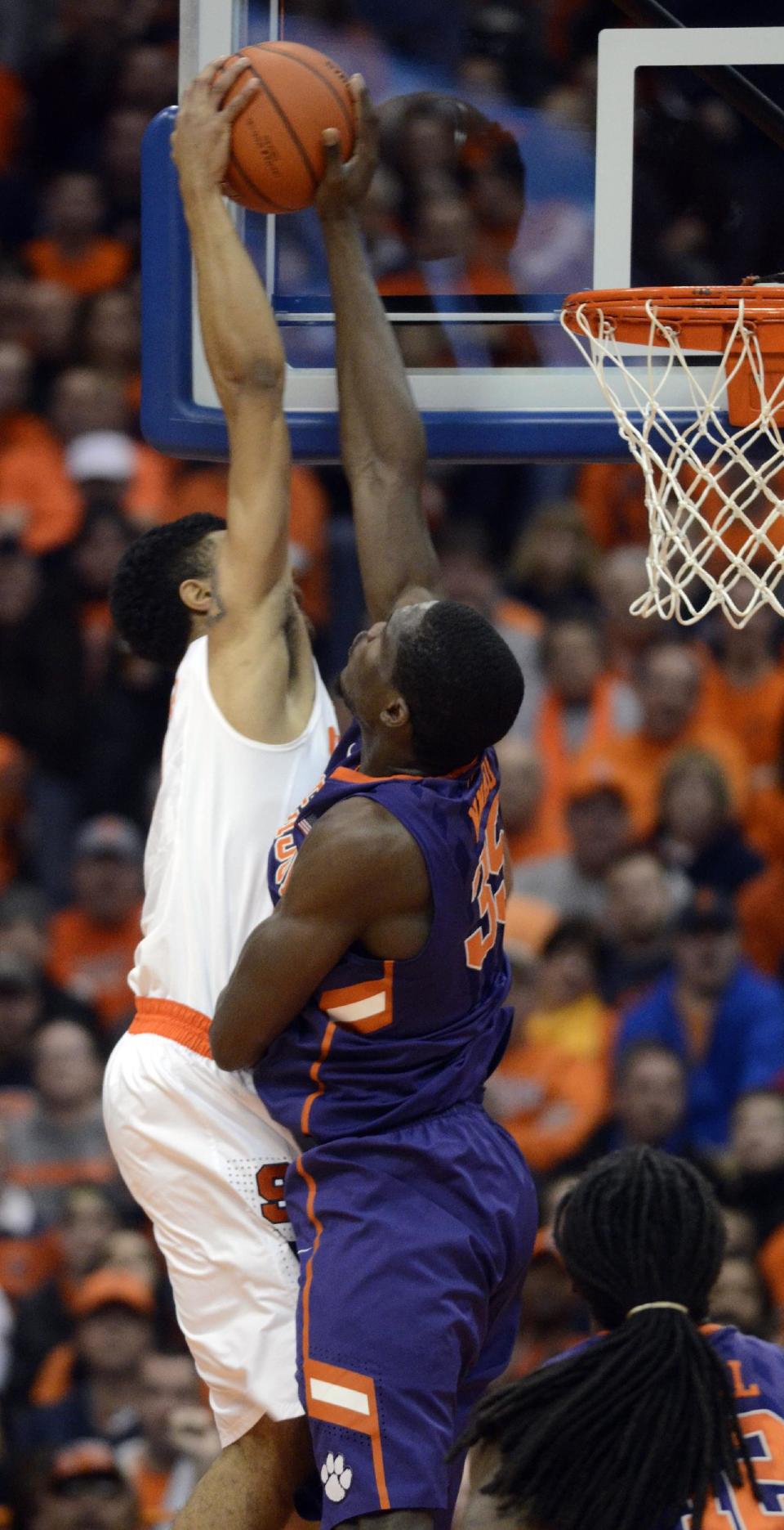 Syracuse's Michael Gbinije, left, has his shot rejected by Clemson's Landry Nnoko during the first half of an NCAA college basketball game in Syracuse, N.Y., Sunday, Feb. 9, 2014. (AP Photo/Kevin Rivoli)