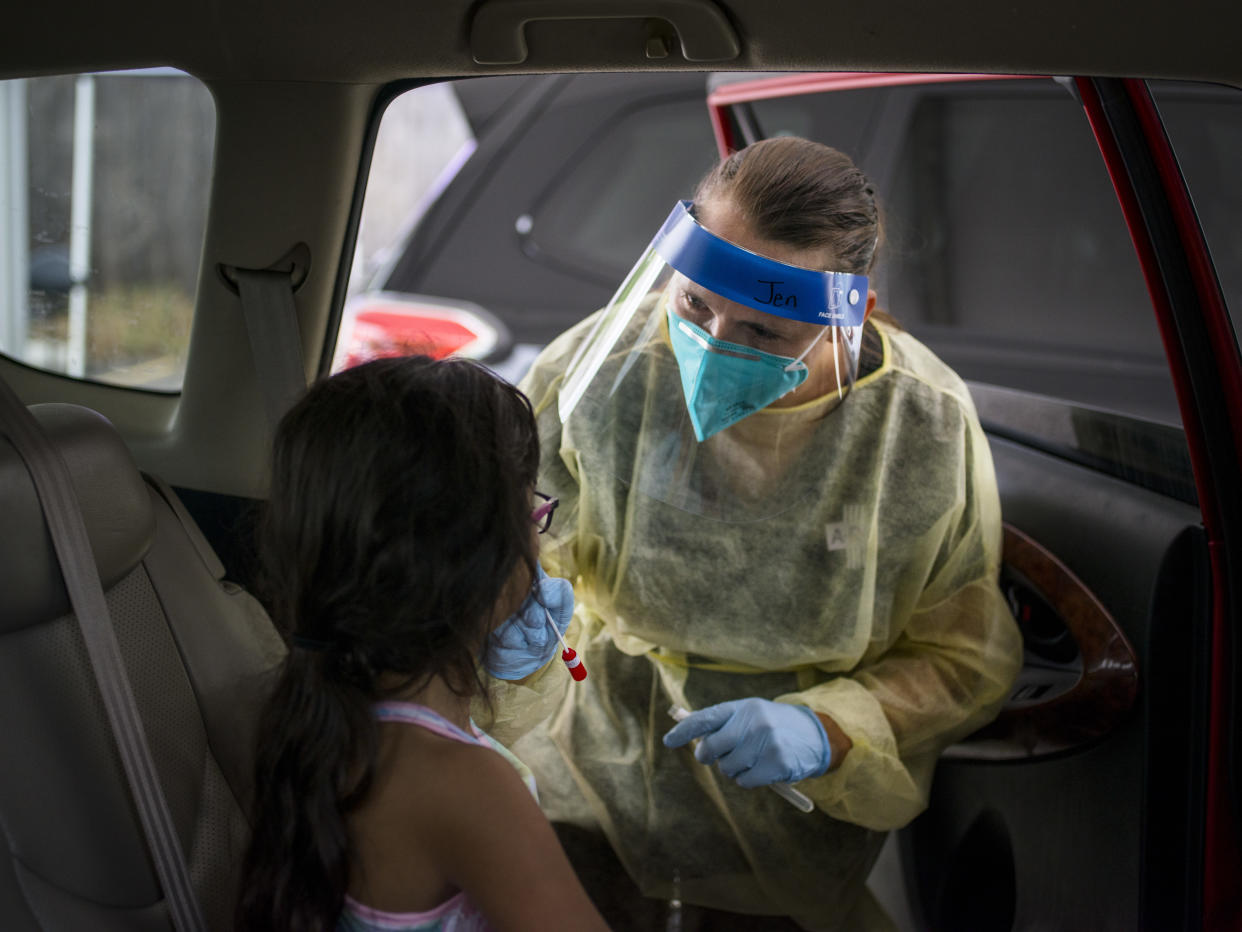A health care worker administers a COVID-19 test to a child at an Austin, Texas, drive-thru vaccination and testing site on Aug. 5, 2021.