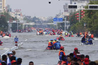 Rescuers use boats to evacuate people from a flooded area in Weihui in central China's Henan Province, Monday, July 26, 2021. Residents laid flowers on Tuesday at the entrance of a subway station where more than a dozen people died after a record-breaking downpour flooded large swaths of Henan province in central China. (Chinatopix via AP)