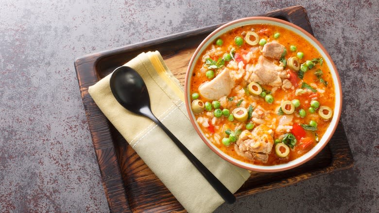 bowl of asopao on wooden tray with spon