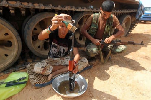 Libyan National Transitional Council (NTC) fighters clean their rifles at an outpost on the outskirts of Sirte. Libya's new rulers on Thursday stepped up the hunt for Moamer Kadhafi's inner circle, seeking the arrest of one of his sons, Saadi, amid conflicting reports of the capture of his spokesman Mussa Ibrahim