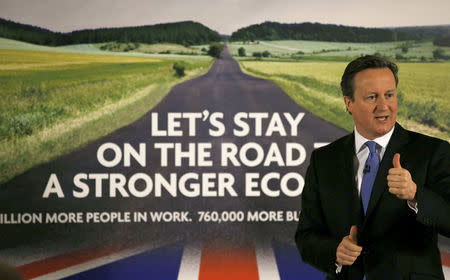 Britain's Prime Minister David Cameron speaks as he stands in front of a new Conservative Party poster, after unveiling it at Dean Clough Mill in Halifax, northern England January 2, 2015. REUTERS/Phil Noble