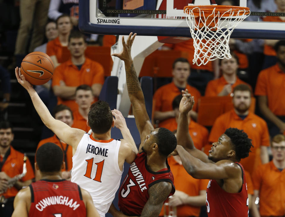 Virginia guard Ty Jerome (11) goes up to shoot as Louisville forward V.J. King (13) and Louisville center Steven Enoch, right defend during the first half of an NCAA college basketball game in Charlottesville, Va., Saturday, March 9, 2019. (AP Photo/Steve Helber)