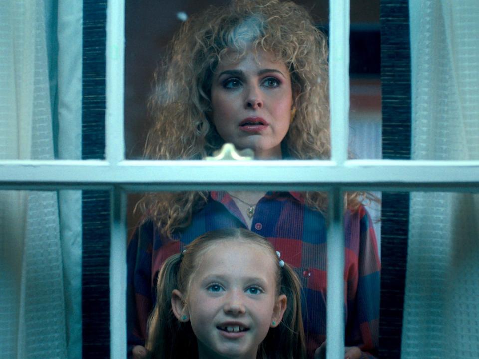 A scene from "Stranger Things" season four showing Karen and Holly (an older woman and her young daughter) looking out a window.