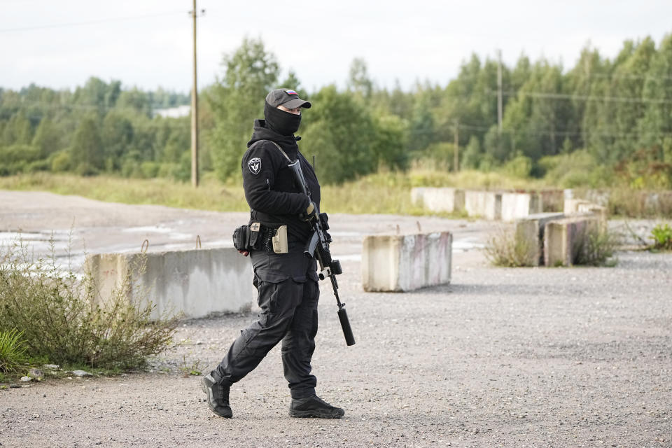 A Russian serviceman guards a road near a private jet crash, near the village of Kuzhenkino, Tver region, Russia, Thursday, Aug. 24, 2023. Russian mercenary leader Yevgeny V. Prigozhin, the founder of the Wagner Group, reportedly died when a private jet he was said to be on crashed on Aug. 23, 2023, killing all 10 people on board. (AP Photo/Alexander Zemlianichenko)