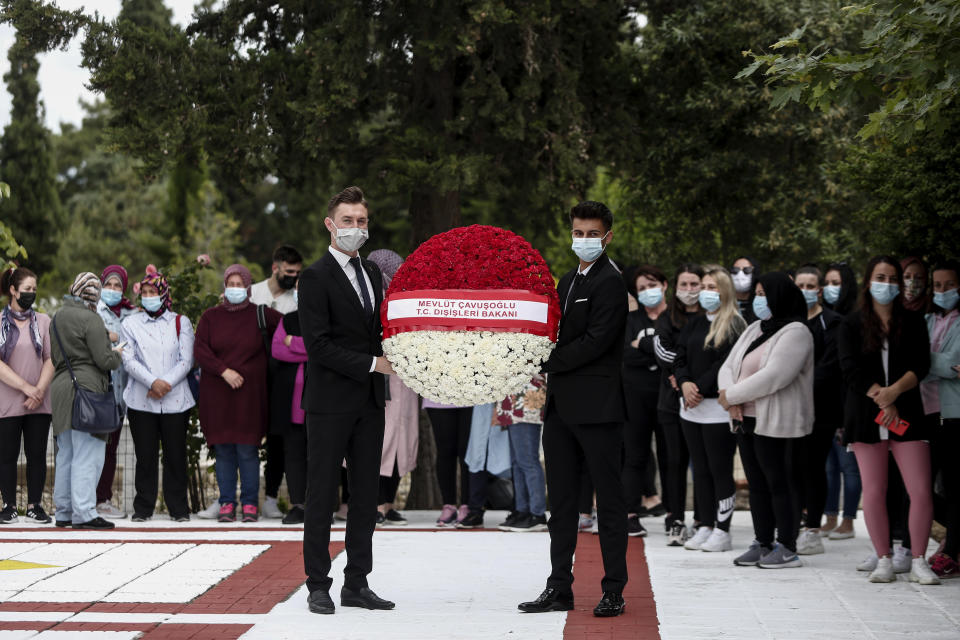 Two youths hold a wreath which is to be laid by Turkish Foreign Minister Mevlut Cavusoglu at a muslim cemetery at Komotini town, in northeastern Greece, Sunday, May 30, 2021. Greece's prime minister said Friday his country is seeking improved ties with neighbor and longtime foe Turkey, but that the onus is on Turkey to refrain from what he called "provocations, illegal actions and aggressive rhetoric." (AP Photo/Giannis Papanikos)