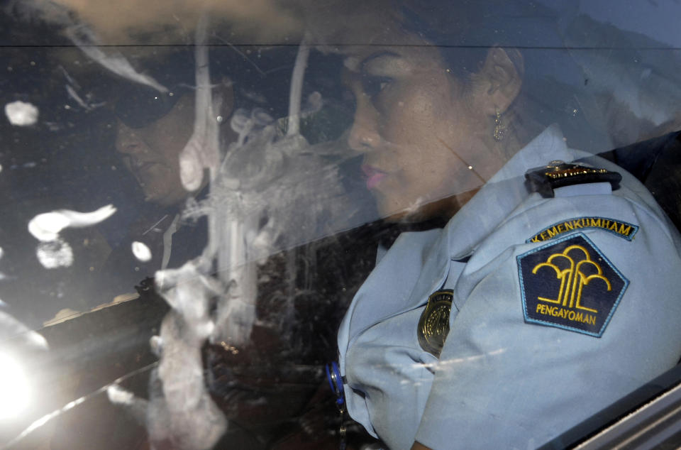 Australia drug smuggler Renae Lawrence, left, sits in a car as she escorted by an immigration officer in Bali, Indonesia, Wednesday, Nov. 21, 2018. Lawrence Indonesia has freed an Australian woman who served nearly 14 years in prison for smuggling heroin into the tourist island of Bali. (AP Photo/Dana Pradana)