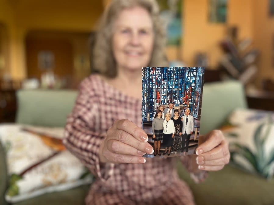 
            woman holding photo of herself and priest

        
