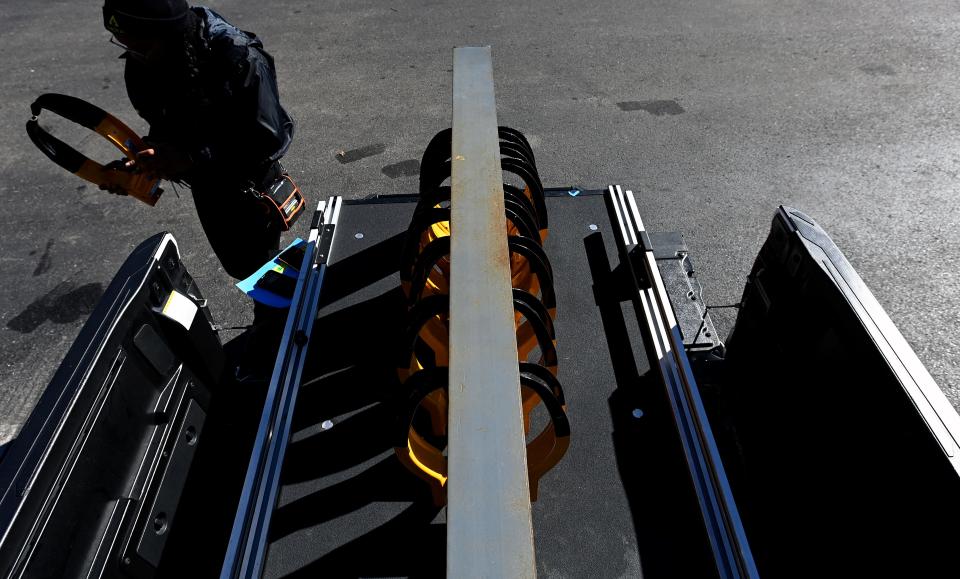 An employee of Admiral Parking Enforcement prepares a boot in a paid parking lot on Monday, Feb. 19, 2024, in Nashville, Tenn. Local and officials are working on stronger regulations for the companies that boot cars. Unlike some companies that provide no grace period, Admiral Parking gives drivers 30 minutes to move their vehicles before attaching a boot to the back driver’s side wheel.