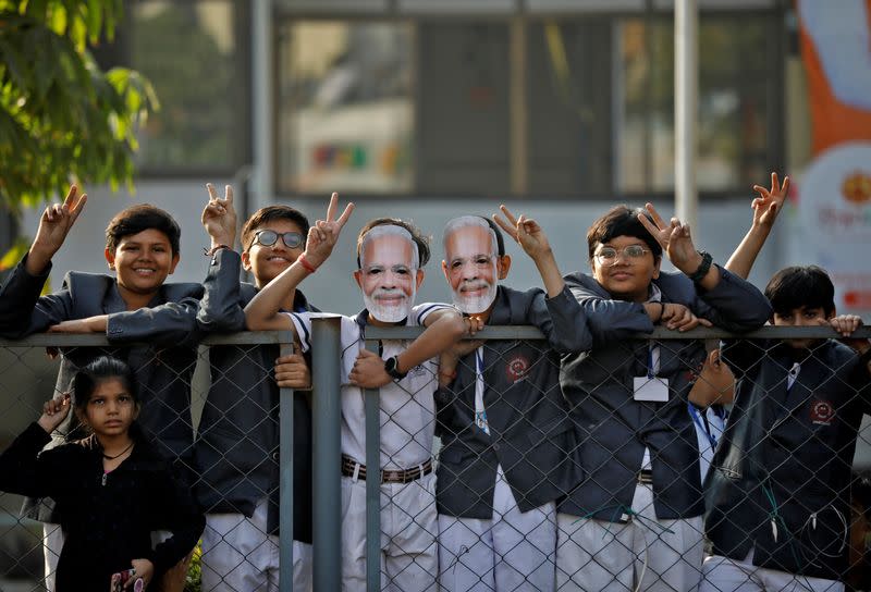 School children gesture towards India's Prime Minister Narendra Modi as he arrives to cast his vote, in Ahmedabad