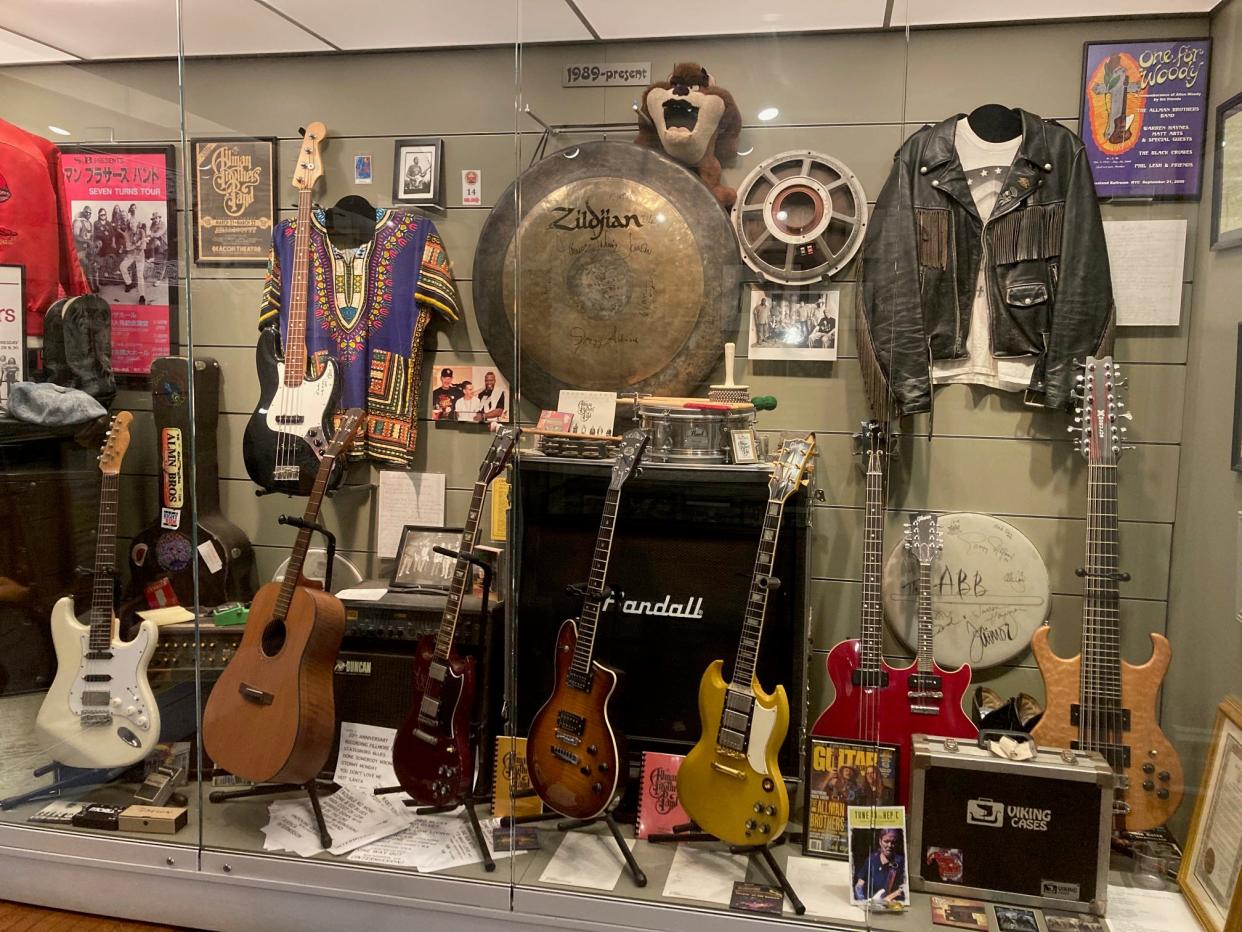 A curated display of garments and instruments at The Allman Brothers Band Museum.