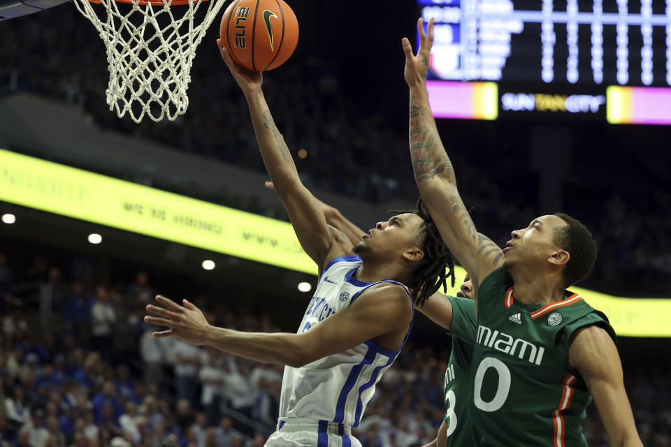 Kentucky's D.J. Wagner, left, shoots while pressured by Miami's Matthew Cleveland (0) during the first half of an NCAA college basketball game in Lexington, Ky., Tuesday, Nov. 28, 2023. (AP Photo/James Crisp)