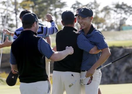 International team member Bae Sang-moon (R) of South Korea celebrates with teammates after sinking his putt to defeat U.S. team member Rickie Fowler and Jimmy Walker on the 18th hole during the four ball matches of the 2015 Presidents Cup golf tournament at the Jack Nicklaus Golf Club in Incheon, South Korea, October 9, 2015. REUTERS/Toru Hanai