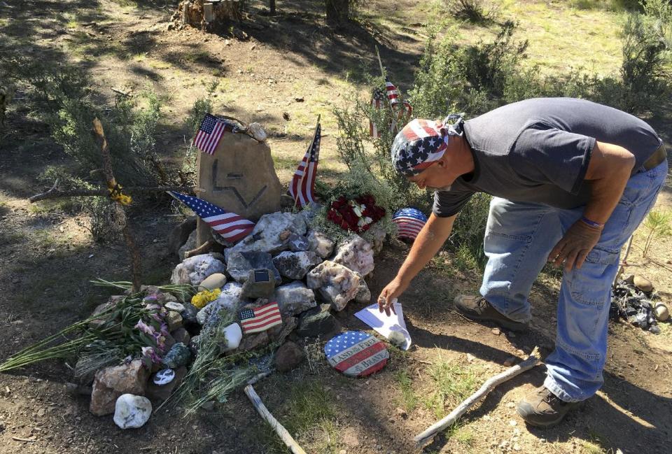 FILE--In a June 21, 2016 file photo, John Hildinger, of Corpus Christi, Texas, tends to a memorial for LaVoy Finicum at the spot where Finicum, one of the armed occupiers of the Malheur National Wildlife Refuge, was killed by police at a roadblock near Burns, Ore. Finicum's widow, Jeanette Finicum, and their children are planning to hold a meeting in John Day, Ore., Jan. 28, 2017, in an effort to continue with his mission. (AP Photo/Andrew Selsky)