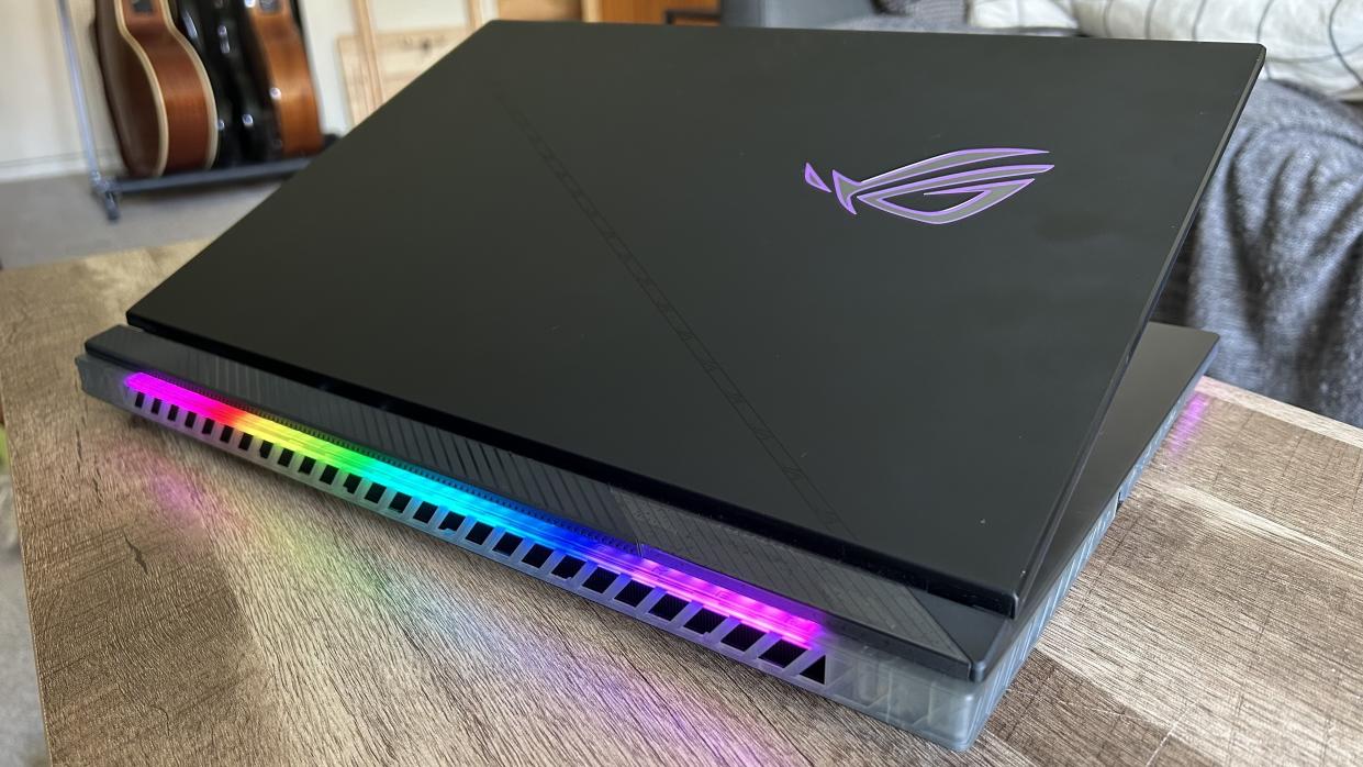  Asus ROG Strix Scar 18 gaming laptop with lid half closed on a wooden table. 