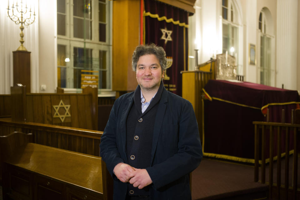 This Wednesday, March 20, 2019 photo Jonathan Marcus a German member of 'Fraenkelufer' synagogue poses for a photo inside the prayer room of the so-called youth-synagogue, the remaining building of the 'Fraenkelufer' synagogue, in Berlin. The synagogue was able to receive about 2000 prayers before it was destroyed by the Nazis. In the German capital, efforts are underway to rebuild the synagogue. (AP Photo/Markus Schreiber)