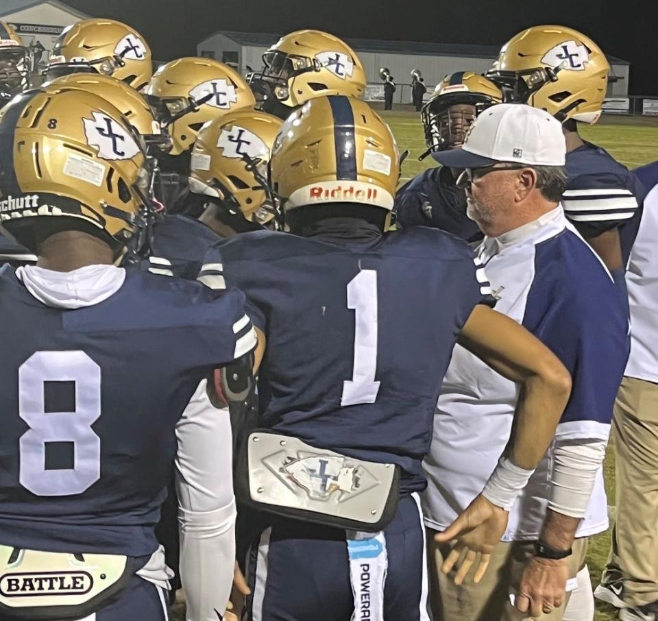 Coach JB Arnold talks to his players on the sideline during a game.