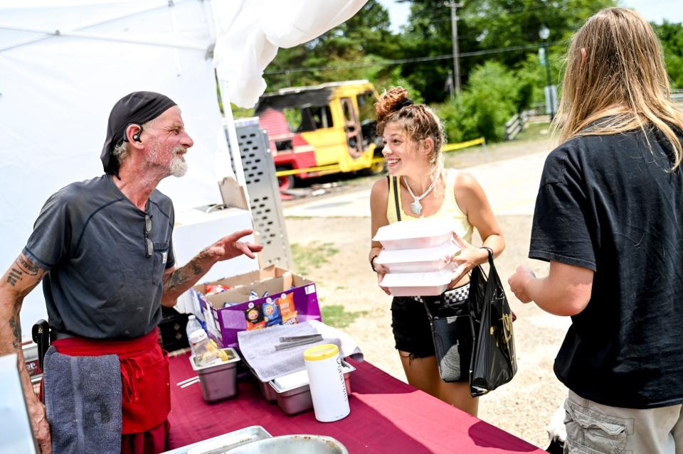 Truckin' Awesome owner Marty Martin, of Charlotte, left, talks with customers Haylie Vanderwal, center, and Jack Smith in the parking lot of the Double Nickel Party Store and gas station on Monday, July 10, 2023, in Olivet. Martin died on Saturday.