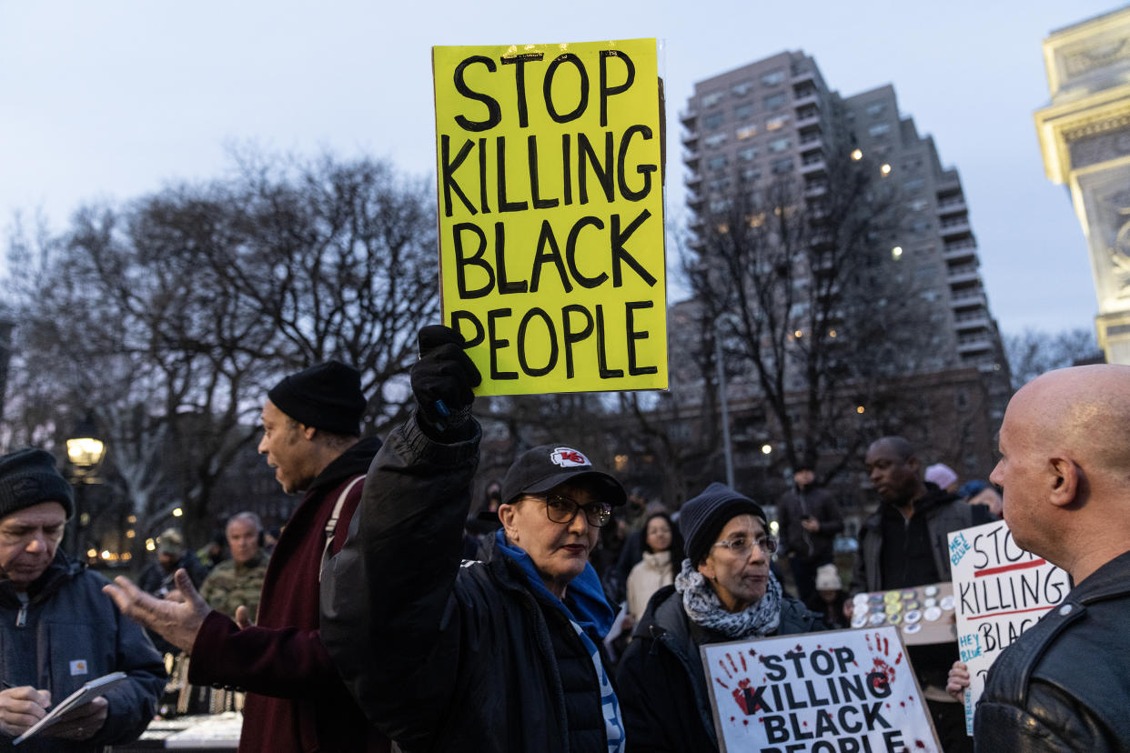 Activists against police brutality hold up signs reading: Stop killing Black people.