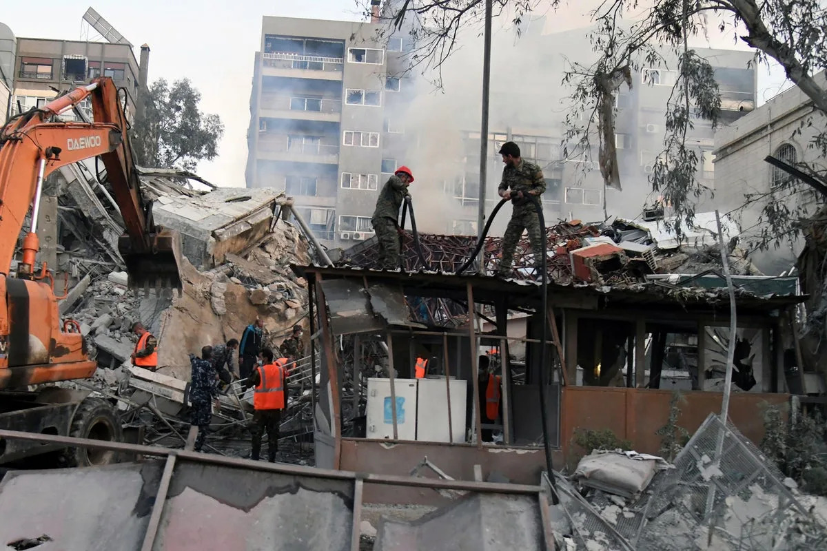 Emergency service workers clear the rubble at a destroyed building struck in Damascus (ASSOCIATED PRESS)