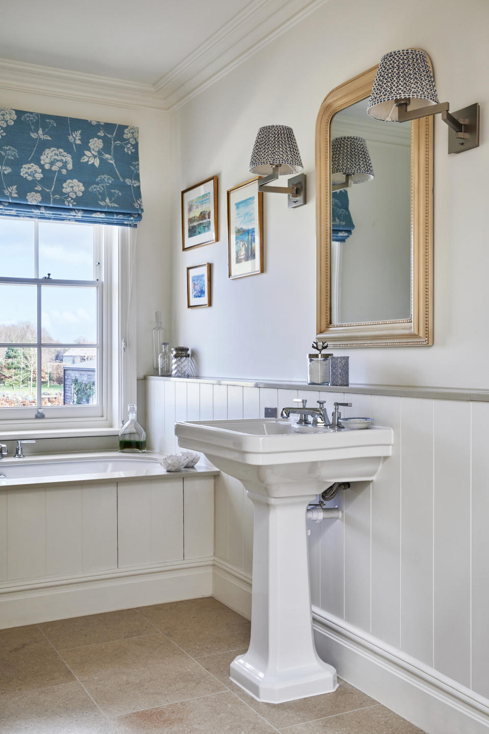 <p> A pretty fabric blind, framed artworks and smart wall lights with pleated shades look as at home in a country bathroom as they do in a sitting room. Importantly, they bring softness and colour to this often cold and functional space. </p> <p> Coordinate your colour scheme with the adjacent rooms and accessorize with cut-glass and crystal jars for a classic country house look.  </p>