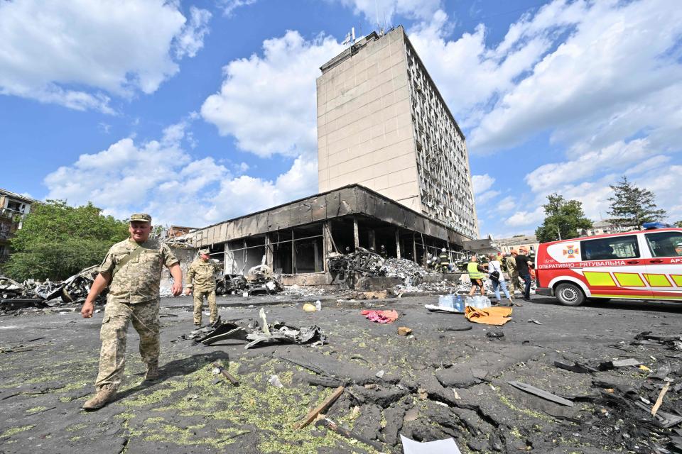 Ukrainian army members and firefighters inspect a damaged building.