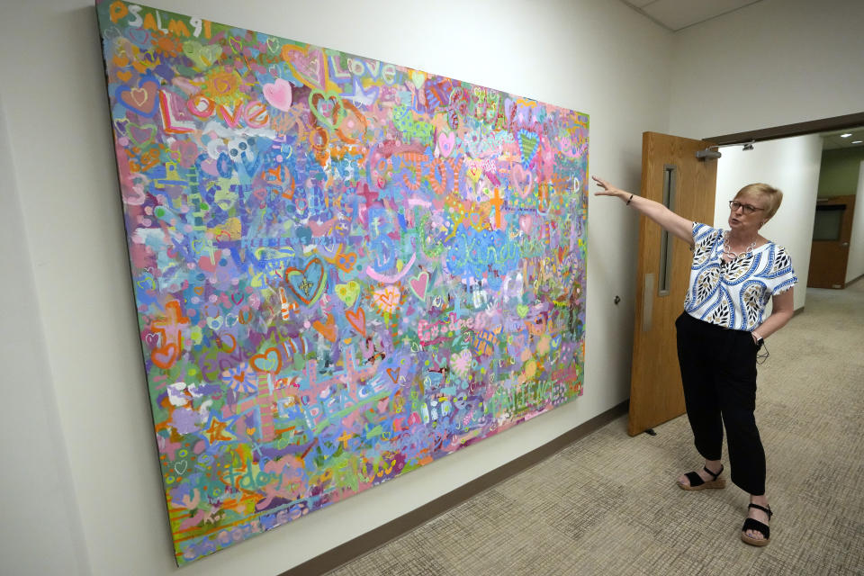 Trudy Waters, the Head of School at The Covenant School in Nashville, Tenn., talks about a large painting done by students and staff at the school Tuesday, June 25, 2024. The canvas contains words and images that serve as a tribute to the three students and three adults killed in a shooting at the school on March 27, 2023. (AP Photo/Mark Humphrey)