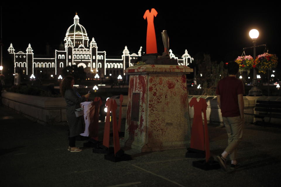 The statue of English explorer Capt. James Cook was vandalized and removed from it's base and tossed into the inner harbor and replaced with red hand prints and a red dress in protest of missing and murdered Indigenous women and girls in Victoria, Thursday, July 1, 2021. (Chad Hipolito/The Canadian Press via AP)