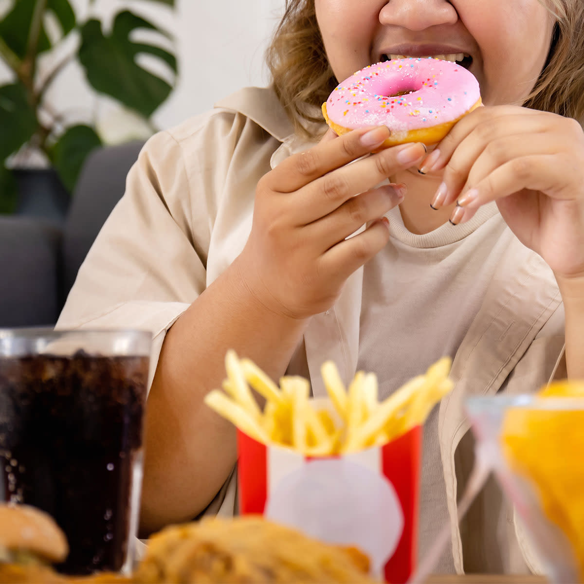 woman eating junk food donuts and fries
