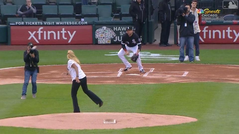 金髮美女朝捕手方向瞄準準備開球，球卻朝著一旁攝影師飛去，直接砸在攝影器材上。（翻攝自MLB官方）