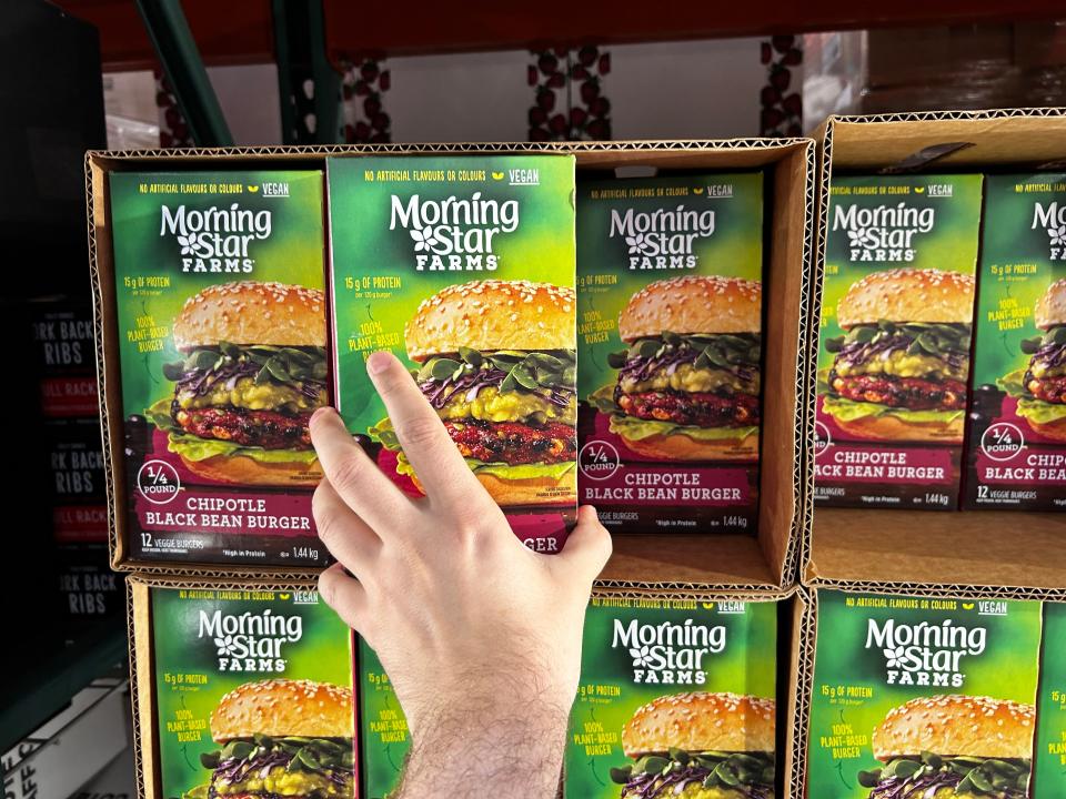 Mackenzie grabbing a box of Morning Star chipotle black-bean patties at Costco.